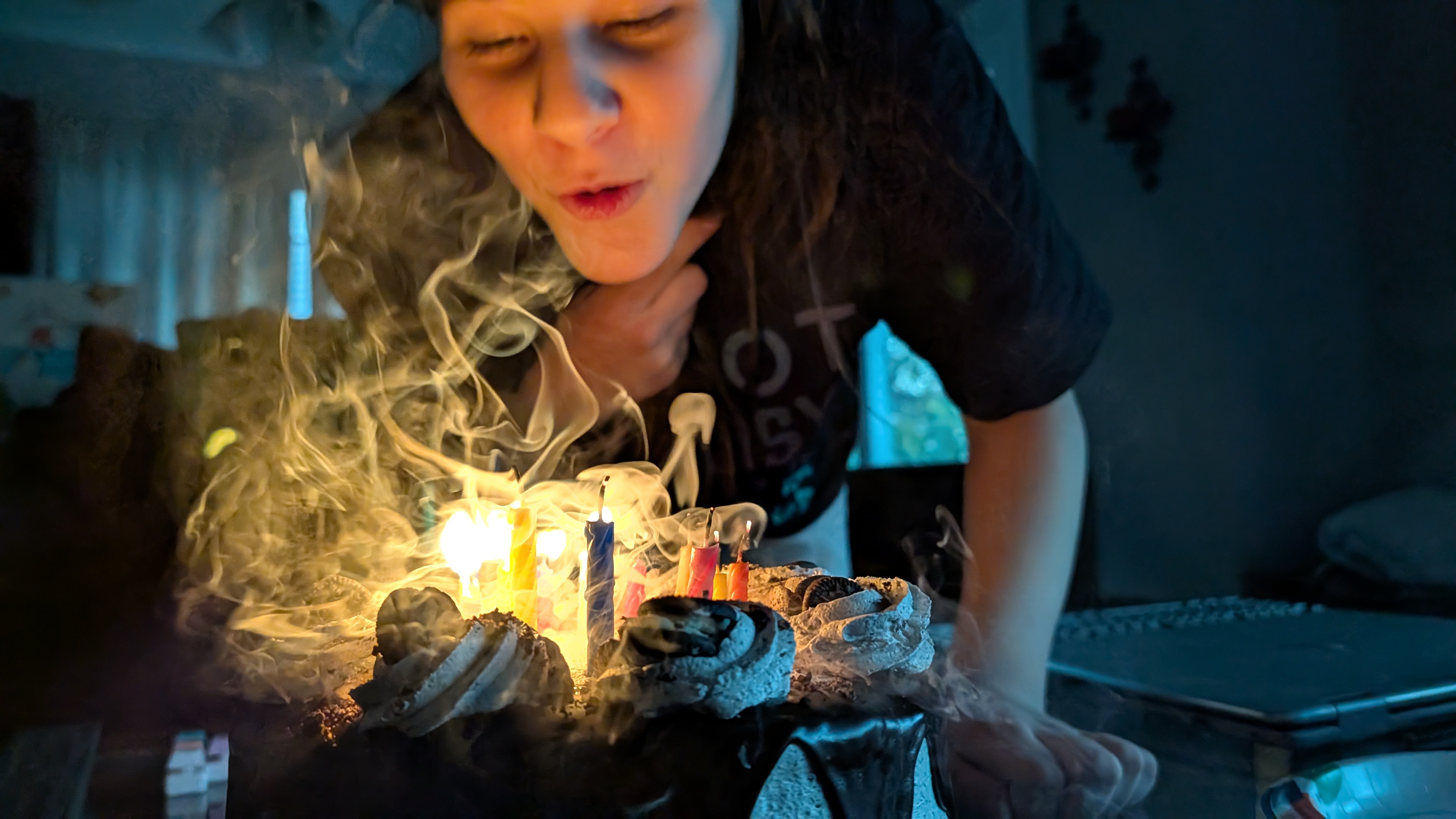 A girl blows out the candles on a birthday cake creating smoke